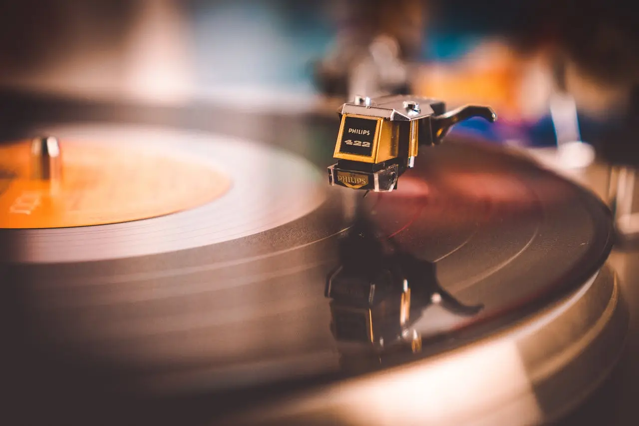 Closeup of a cartridge on the tone arm of a record player playing a 12 inch vinyl record.